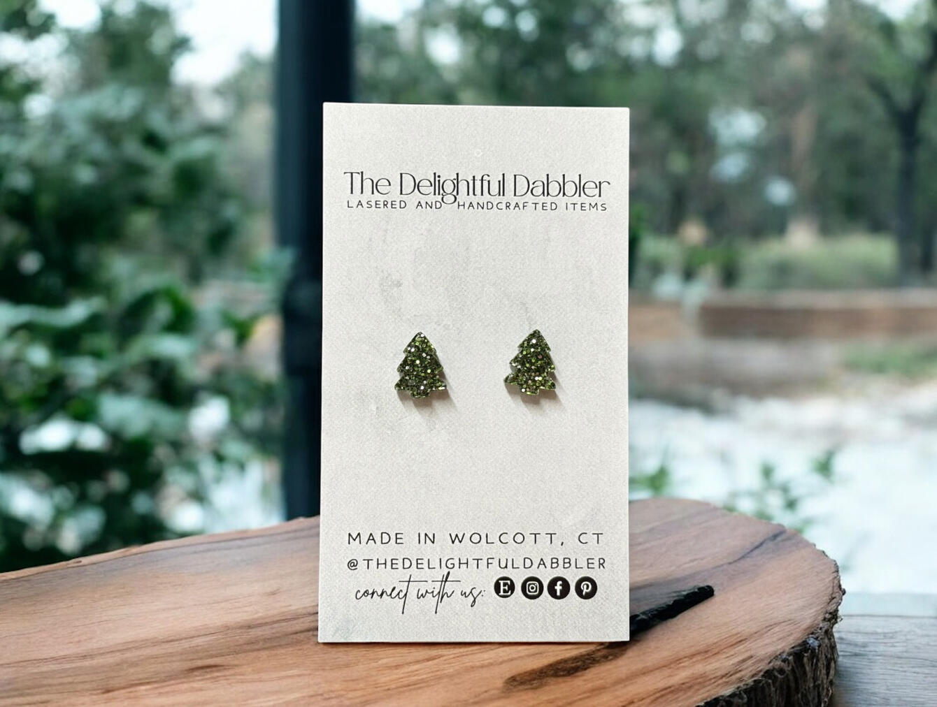 Handmade green glitter Christmas tree earrings, laser cut and displayed on The Delightful Dabbler branded card.